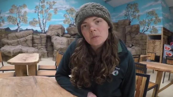 A picture of Maxine Bradley in a cafe wearing a woolly hat and Northumberland Zoo green fleece.