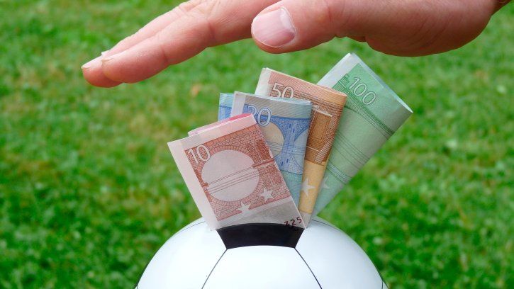 Hand pushing money into a football