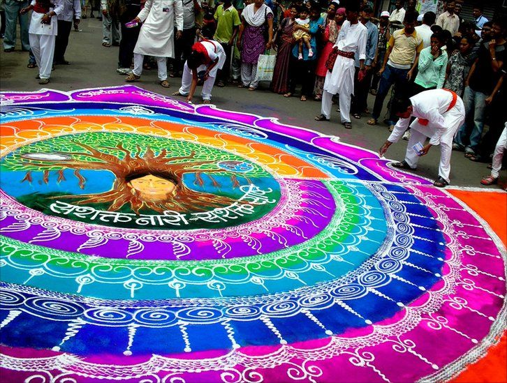 Artists creating designs in coloured powder on the streets of Pune, India during the immersion procession of the annual Ganesha Festival