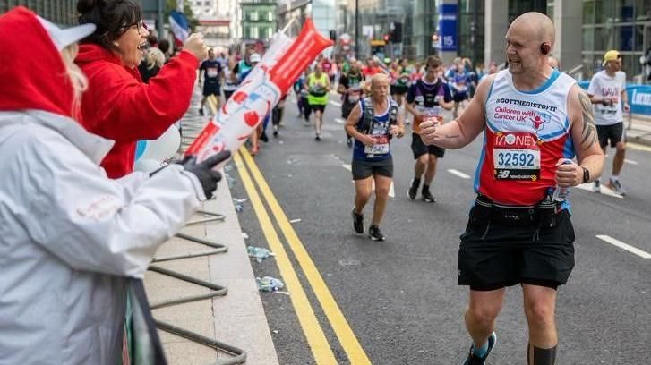 Chris Johnson is pictured to the right of the image with his fist clenched, smiling at a woman encouraging him during the London Marathon