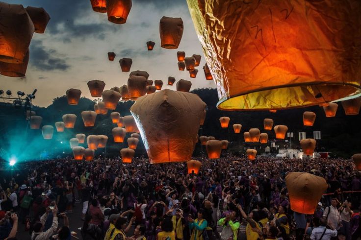 A crowed releases lanterns with flames into the air