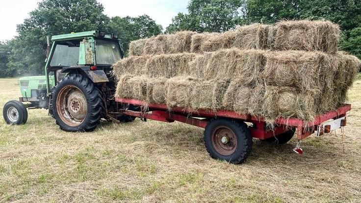 A tractor carrying bales of hay in a field