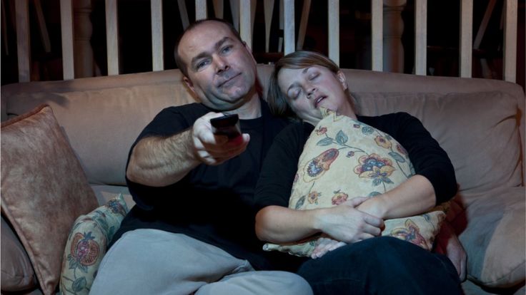 Man and woman falling asleep while watching TV on the sofa