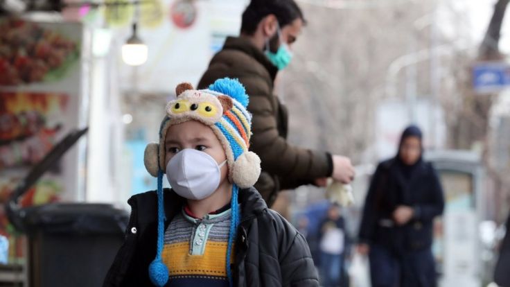 A child wearing a face mask walks on a street in Tehran on 26 February 2020