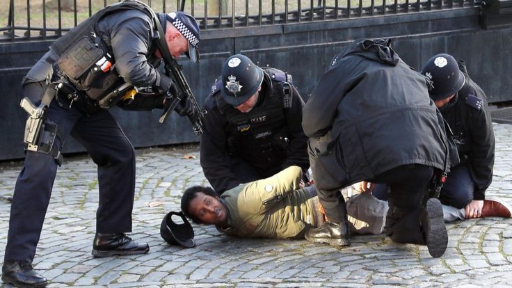 Armed police restrain a man