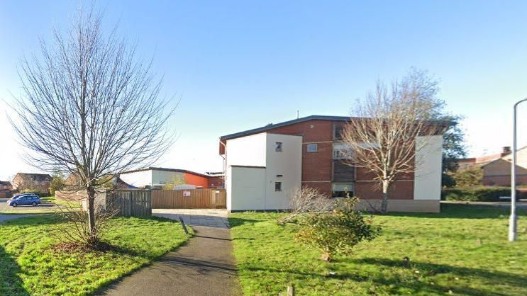 Two story modern health building surrounded by grass and trees in housing estate