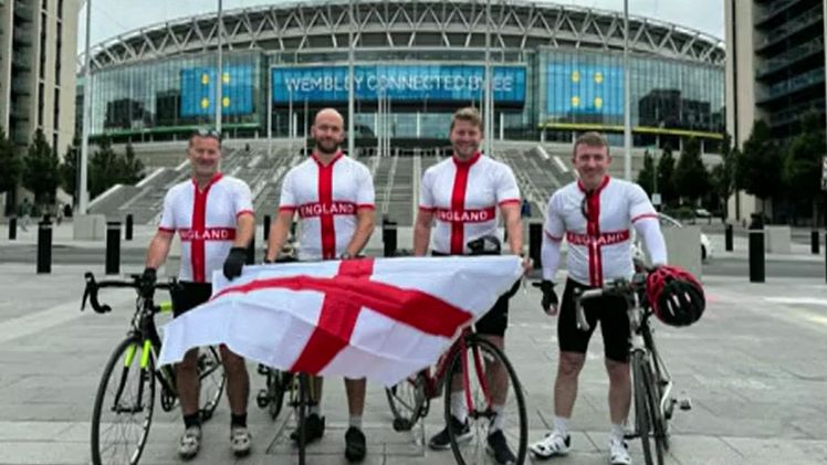 England football fans with bikes posing in front of Wembley stadium