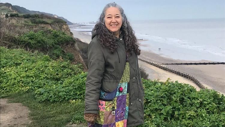 Diane Devereux by a seaside cliff