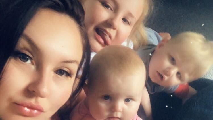 A selfie of Ms Gawith and her children. Strands of her dark hair frame her face. Her children, all blond, are looking directly at the camera. Her daughter at the back has her tongue sticking out.