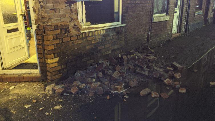 Damage to a house, with bricks and rubble on the ground