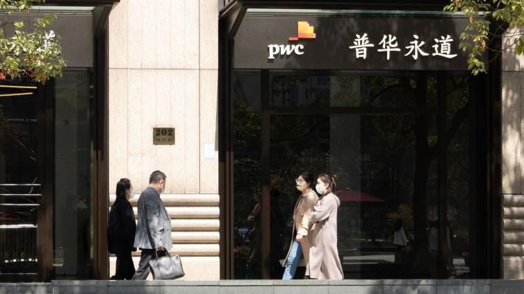 Four people walking past PwC office in Shanghai