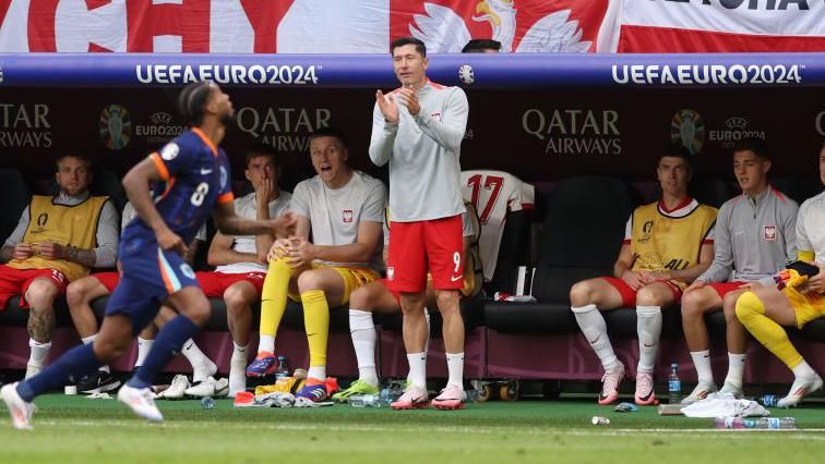 Robert Lewandowski applauds his Poland team-mates from the bench