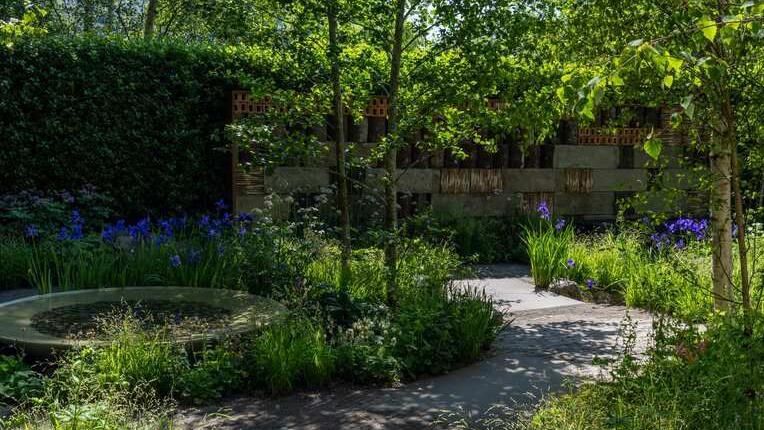 Beautiful garden with purple and white flowers, a water feature and pathways