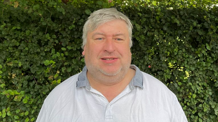 A man wearing a creased white polo shirt