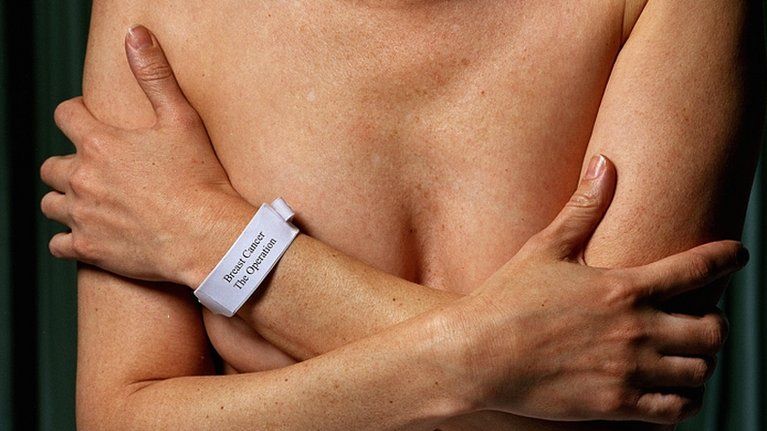 A woman covers her breasts