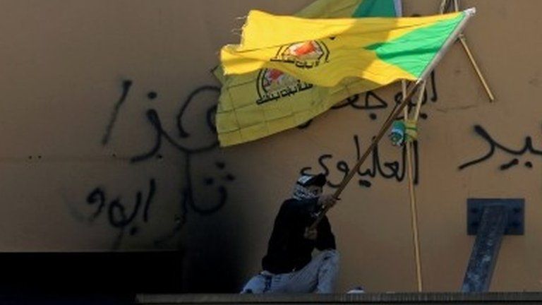 Man waves a Kataib Hezbollah flag outside US embassy in Baghdad (file photo)