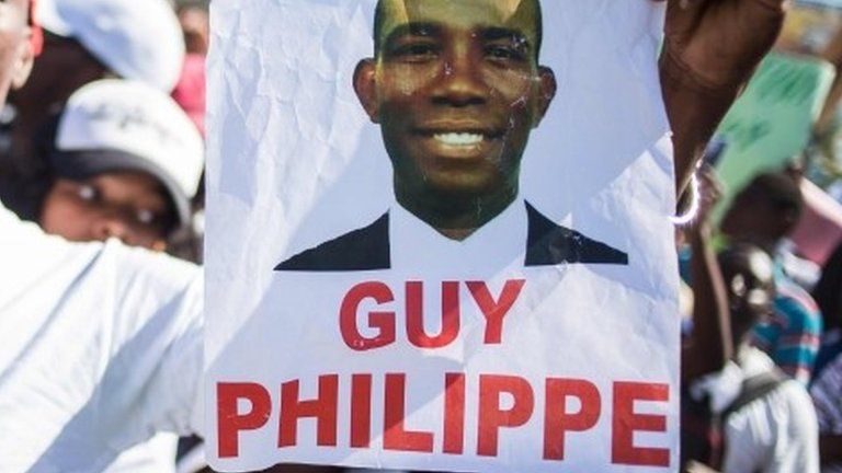This file photo taken on January 13, 2017 shows a supporter of Guy Philippe holding a sign during protests in front of the US embassy in Tabarre a commune of Port-au-Prince.