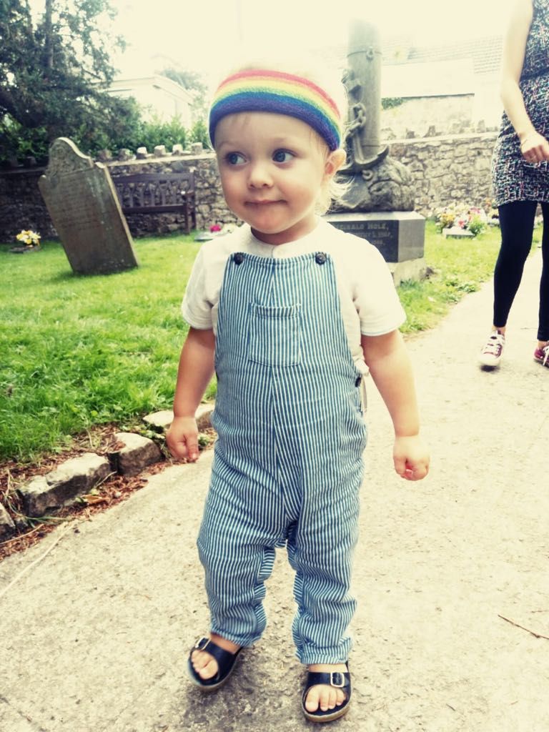 Little boy in dungarees and a rainbow hat