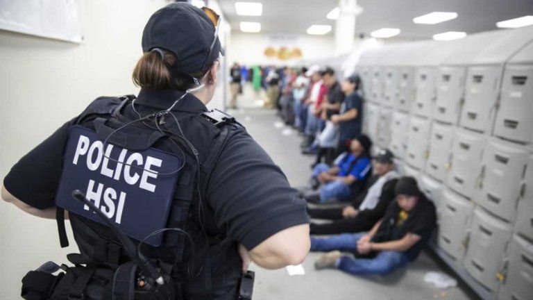 This image released by the US Immigration and Customs Enforcement (ICE) shows a Homeland Security Investigations (HSI) officer guarding suspected illegal aliens on August 7, 2019