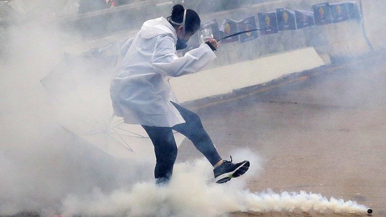 A protester is seen kicking away a tear gas pellet