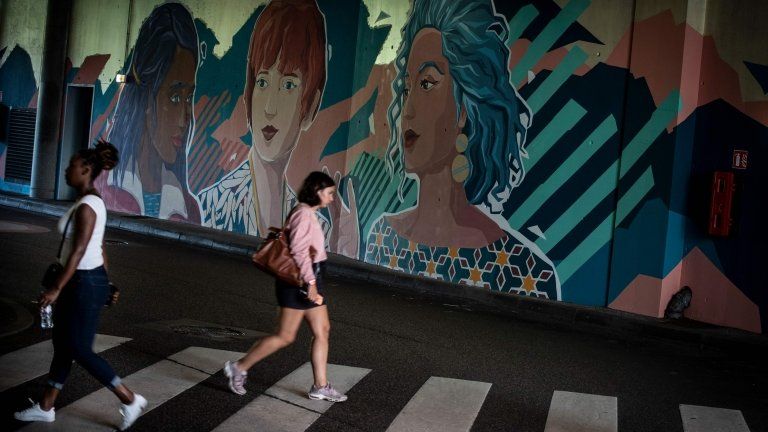 Women walk past a fresco depicting women in a tunnel at the Vaise railway station in Lyon on 12 September 2018