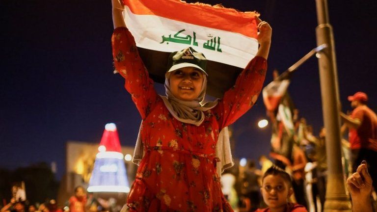 A young supporter of Shia cleric Moqtada al-Sadr holds up an Iraqi flag at a rally in Baghdad held after the initial results of Iraq's election were announced (11 October 2021)