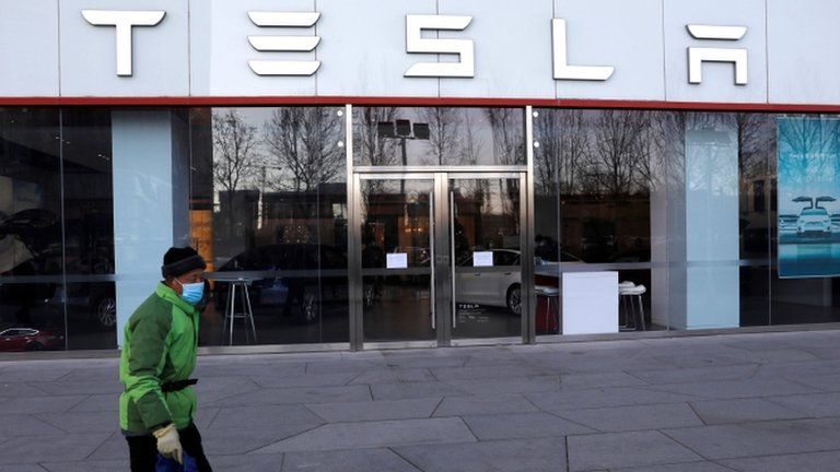 A cleaning worker walks past the electric vehicle maker Tesla"s showroom in Beijing, China January 5, 2021.