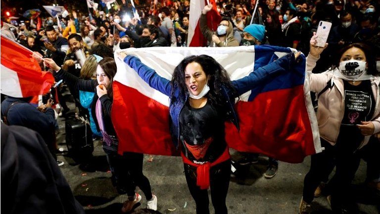 A woman holds a Chilean flag as she reacts to the referendum on a new Chilean constitution in Valparaiso, Chile, October 25, 2020.
