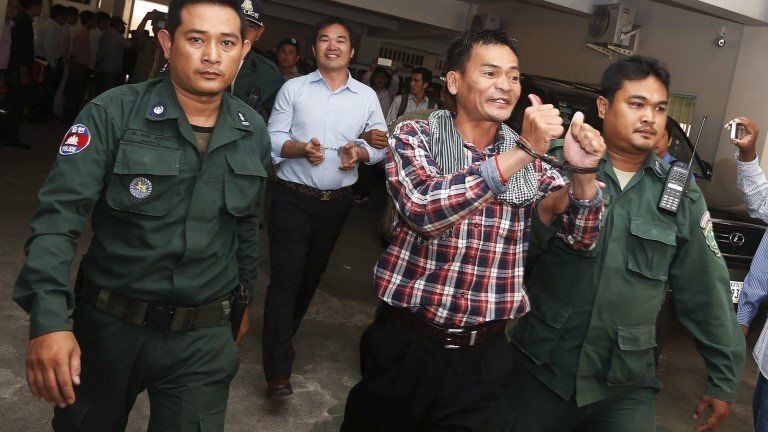 Supporters of the Cambodia National Rescue Party (CNRP), are escorted by Cambodian police officers at the Phnom Penh Municipal Court, 21 July 2015
