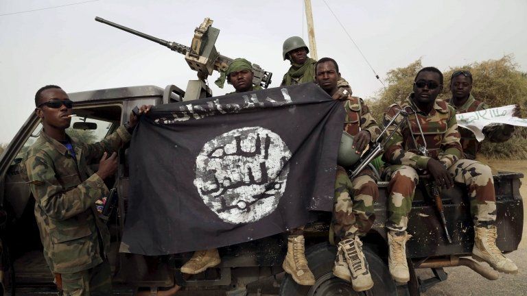 Nigerian soldiers holding up a Boko Haram flag captured in 2015