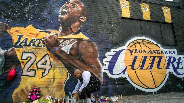 A man lights a candle in front of a Kobe Bryant mural in downtown Los Angeles on 26 January 2020
