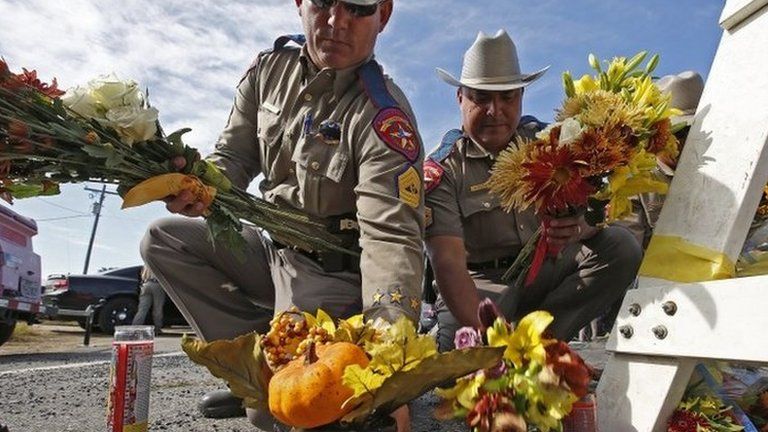 Texas State Troopers move flowers left in tribute to victims of the Sutherland Springs church shooting, 6 November 2017