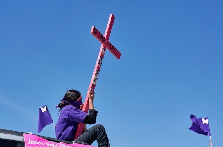 A mother seen atop a vehicle holding a cross with a sign reading "Not one more" during a caravan demanding an end to violence against women and femicide, ahead of a Women"s Day protest, in Ciudad Juarez, Mexico March 7 , 2021
