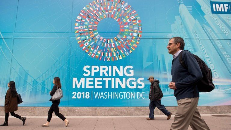 People walk past the IMF headquarters during the 2018 spring meetings of the International Monetary Fund and World Bank in Washington