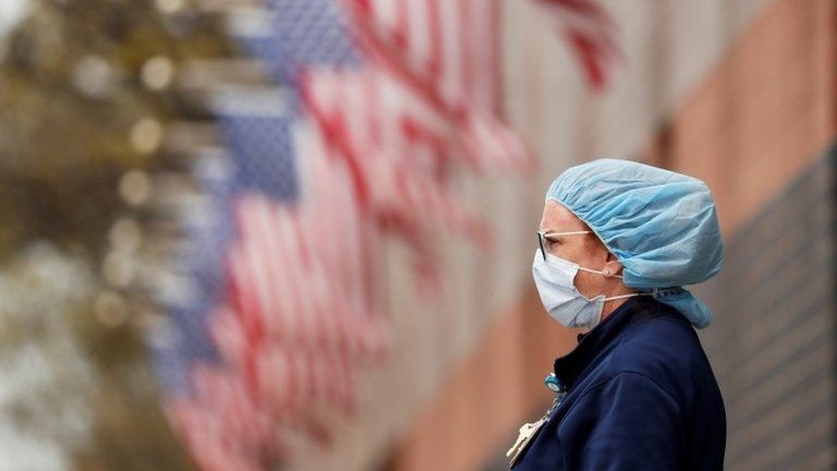 A nurse wearing personal protective equipment watches an ambulance driving away outside of Elmhurst Hospital during the ongoing outbreak of the coronavirus disease (COVID-19) in the Queens borough of New York, U.S., April 20, 2020