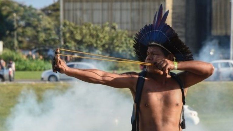A member of an indigenous group uses a sling at a protest in Brasilia on 25 April 2017