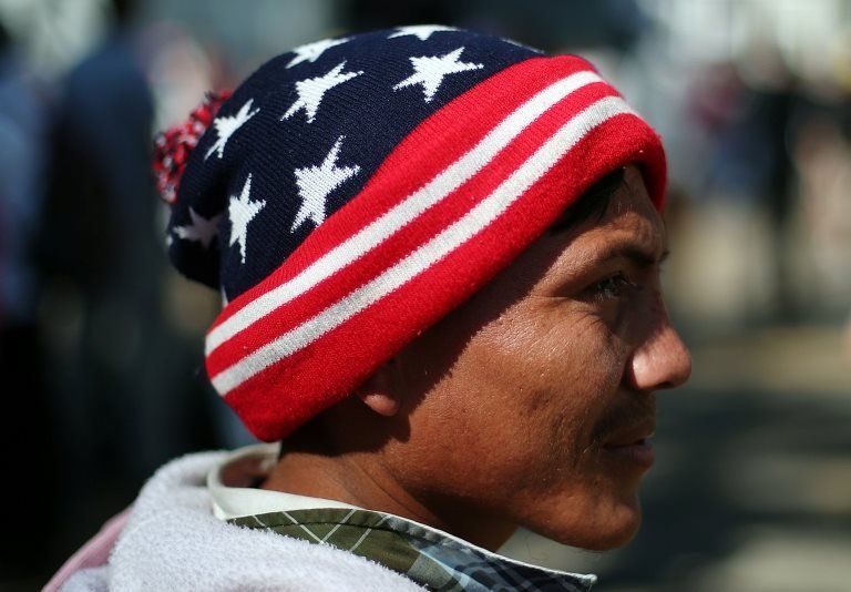 A migrant wears a woolly hat in the colours of the US flag