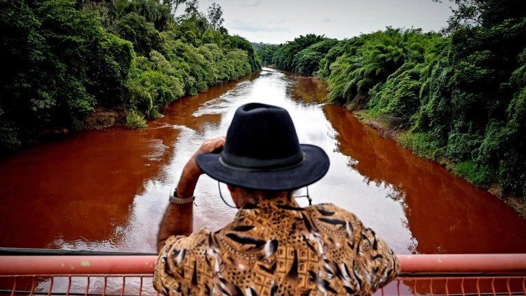 A man watches the Paraopeba River with mud and waste from the disaster caused by dam spill in Brumadinho, Minas Gerais, Brazil, 26 January 2019.