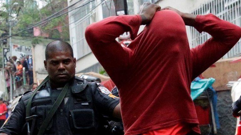 A police officer arrests a suspected drug dealer after a shootout during a police operation at Pavao-Pavaozinho slum