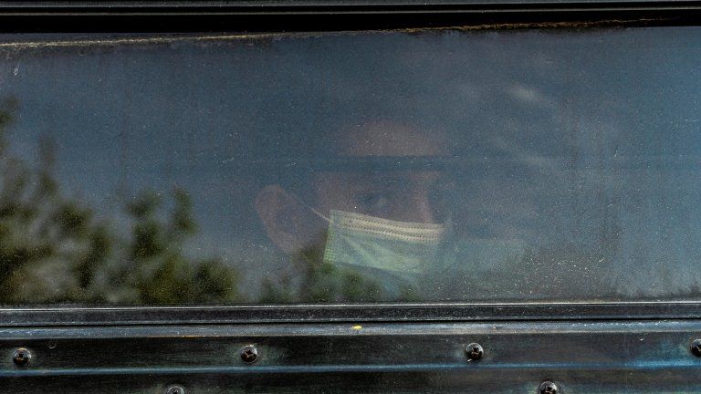 A migrant child seen through the window of a bus