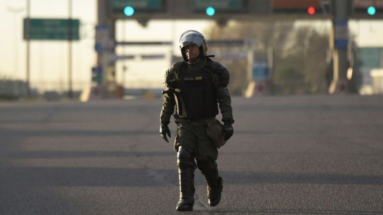 A policeman in riot gear stands guard as demonstrators block the Pan-American highway in Buenos Aires on June 25, 2018, during a 24-hour general strike called by Argentina"s unions