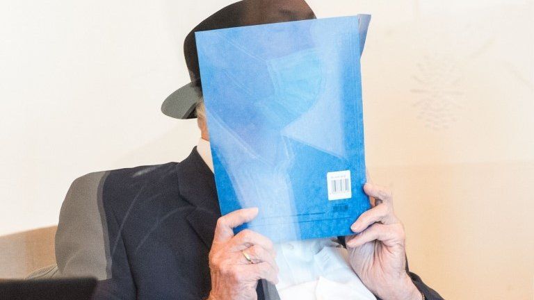 Bruno Dey holds a folder in front of his face in court on 23 July 2020