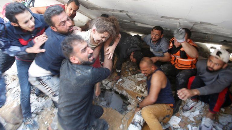 Rescuers carry a girl as they search for victims amid rubble at the site of Israeli air strikes, in Gaza City May 16, 2021.