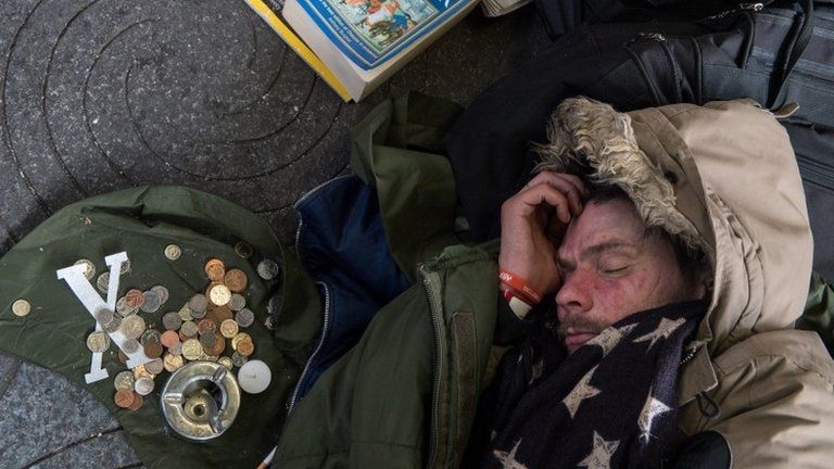 Man sleeping on street next to loose change