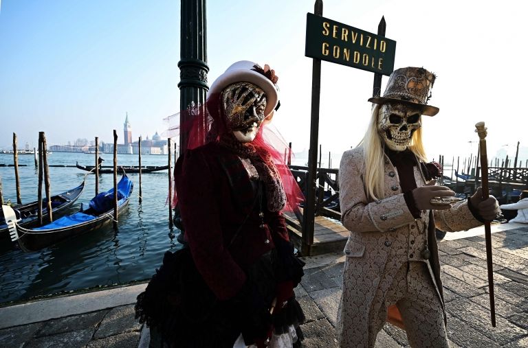 Masked revellers pose in Riva degli Schiavoni during the opening of the Venice Carnival
