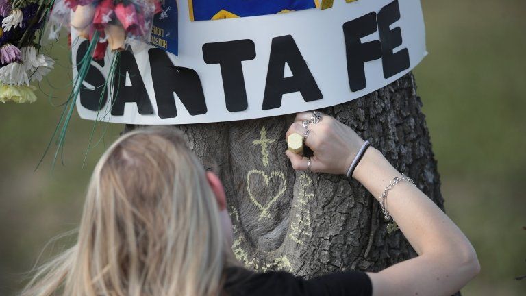 Student chalks a message on a tree outside Santa Fe High School, TX 19 May 2108