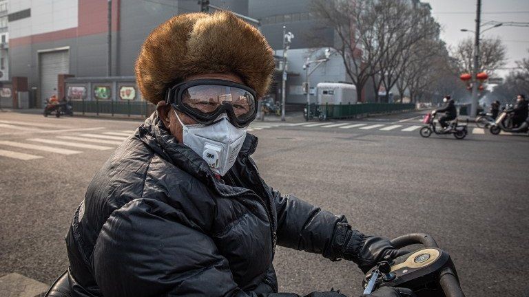 A man wearing a protective face mask and goggles rides on a vehicle in Beijing, China, 11 February 2020.