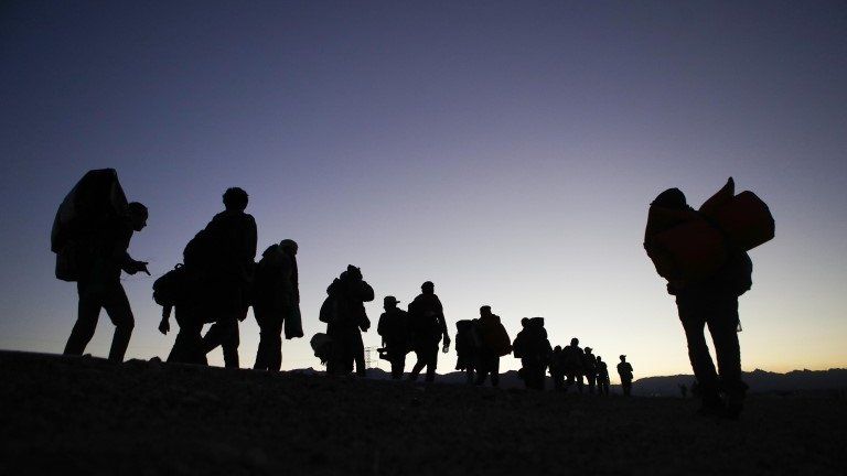 People who are part of the migrant caravan walk at dusk on their way to Tijuana on 20 November, 2018