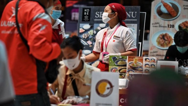 Nhân viên một nhà hàng bán thức ăn mang đi tại Bangkok tất bật khi số đơn đặt hàng tăng vọt trong ngày đầu của tình trạng khẩn cấp ở Thái Lan