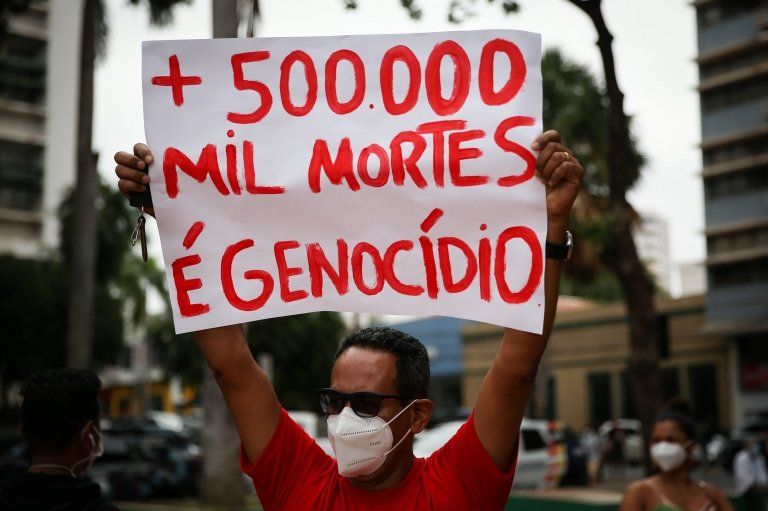 A man at a protest holds a sign calling the deaths genocide